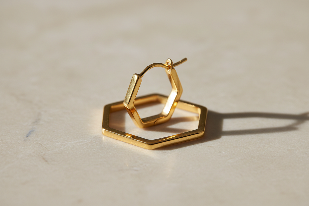 erstelle mir in PNG 1280 x 2000 einen goldenen Ohrring in sechseck hexagon mit 2mm rohrbreite form mit einem  beigen marmor hintergrund